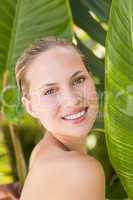 Beautiful blonde smiling at camera behind leaf