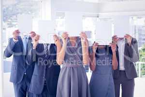 Business colleagues hiding their face with paper