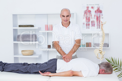 Physiotherapist doing back massage to his patient