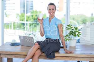 Smiling businesswoman holding disposable cup