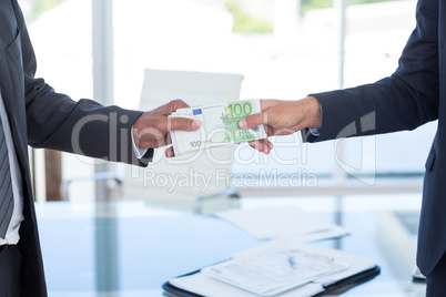 Businessmen shaking hands and exchanging money