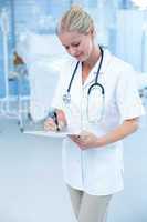 Beautiful smiling doctor writing on clipboard