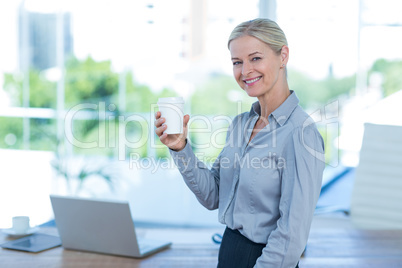 Smiling businesswoman holding disposable cup