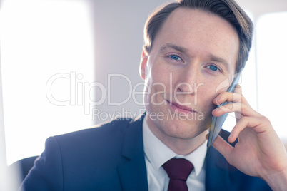 Confident businessman looking at camera while having a phone cal