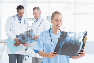 Smiling doctor looking at Xray while her colleagues works