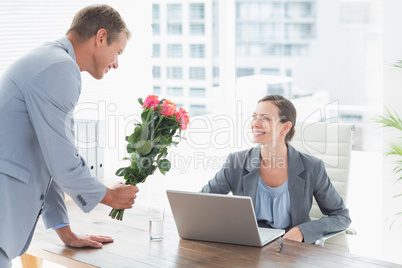 Businessman offering flowers to his colleague