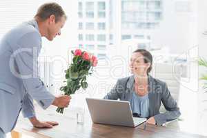 Businessman offering flowers to his colleague