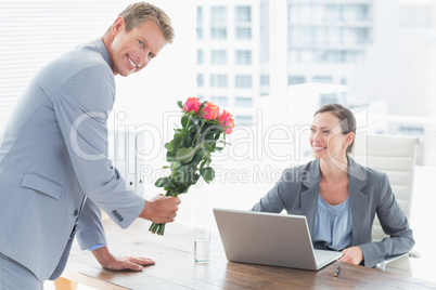 Businessman offering flowers to his colleague