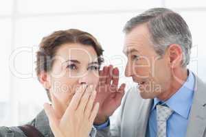 Businessman whispering something to his colleague