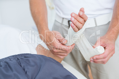 Doctor bandaging his patient hand