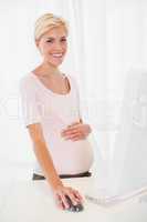 Portrait smiling of a blonde pregnant using computer
