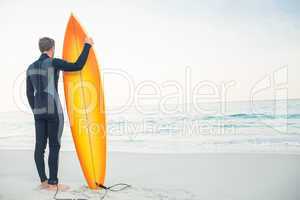 Man in wetsuit with a surfboard on a sunny day