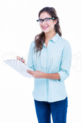 Pretty geeky hipster writing on notebook and smiling at camera