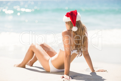 Wear view of blonde woman looking at the sea with santa claus ha