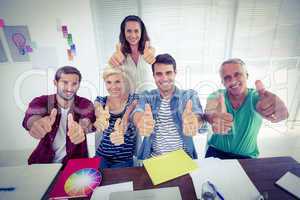 Happy creative business team gesturing thumbs up