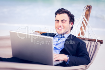 Businessman in a hammock using laptop