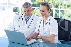 Smiling doctors working together on laptop