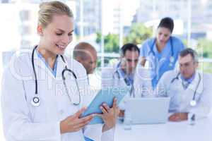 Smiling female doctor looking at clipboard while her colleagues