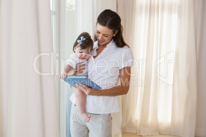 Happy mother with her cute baby girl using tablet