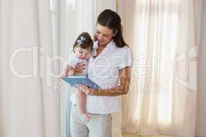 Happy mother with her cute baby girl using tablet