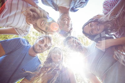 Happy friends huddling in circle in the park