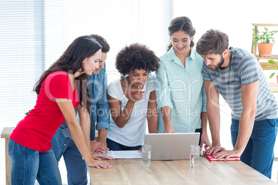 Colleagues gathered around a laptop at office