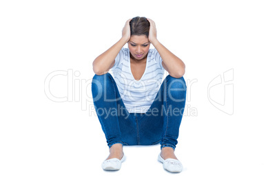 Pretty brunette sitting on floor with headache