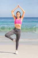 Beautiful fit woman doing yoga beside the sea