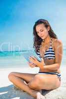 Pretty brunette using tablet pc at the beach