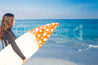 Woman in wetsuit with a surfboard on a sunny day