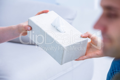 Businesswoman giving paper tissue to her colleague