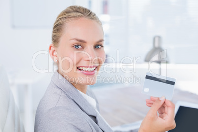 Smiling businesswoman looking at camera with credit card