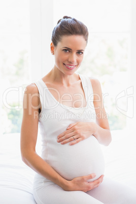 Happy pregnancy sitting on the bed