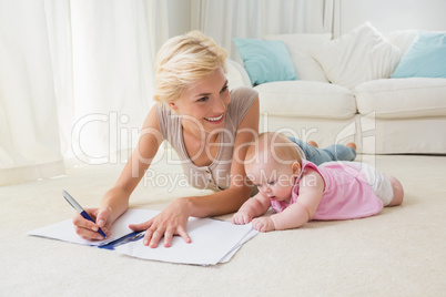 Smiling blonde mother with her baby girl writting on a copybook