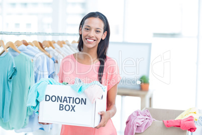 Smiling volonteer holding a box of donations