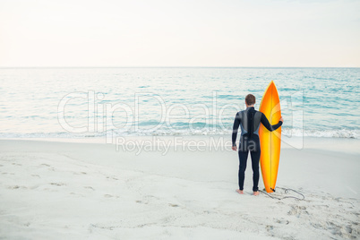 Man in wetsuit with a surfboard on a sunny day