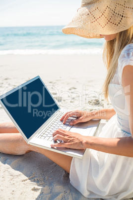 Woman using laptop and wearing hat