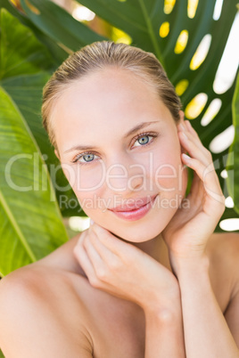 Beautiful blonde smiling at camera behind leaf