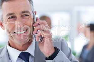 businessman using her phone with two colleague behind him