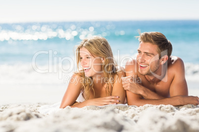 Happy couple relaxing together in the sand