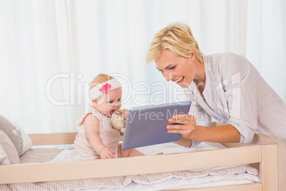 Happy mother with her baby girl using digital tablet