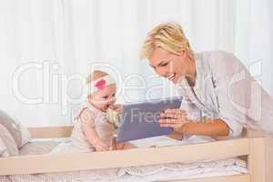 Happy mother with her baby girl using digital tablet