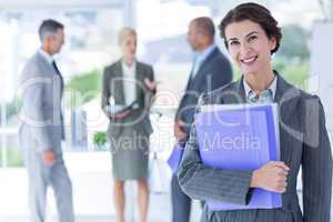 Smiling businesswoman holding files and looking at camera