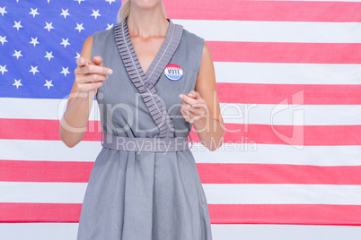 Blonde woman gesturing in front of american flag with badge