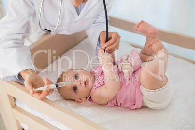 Beautiful baby girl with doctor using syringue and needle