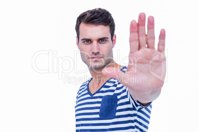 Handsome hipster looking at camera and showing stop sign with ha