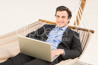 Businessman using laptop on the hammock