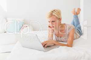 Serious blonde woman using laptop