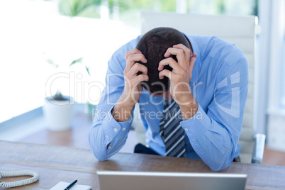 Worried businessman with head in hands