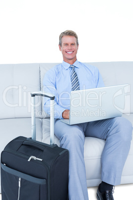 Elegant businessman with laptop sitting on sofa at home